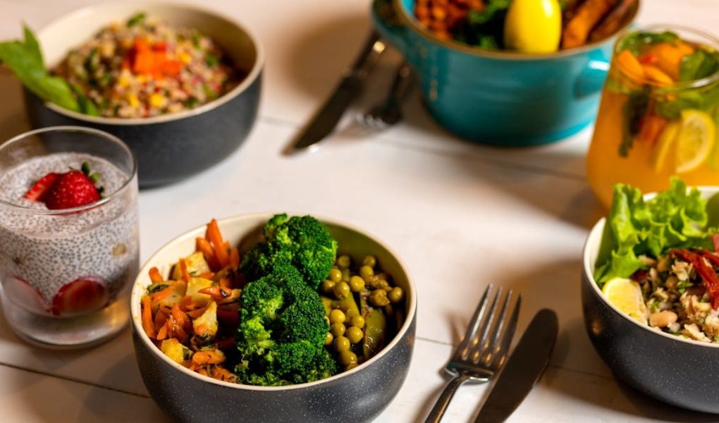 Delicious colorful bowls of salad and fresh beverages on a white table, perfect for healthy dining.