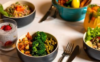 Delicious colorful bowls of salad and fresh beverages on a white table, perfect for healthy dining.
