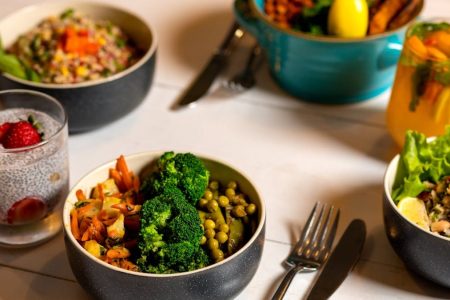 Delicious colorful bowls of salad and fresh beverages on a white table, perfect for healthy dining.